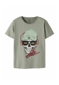 Ljusgrön bomulls-T-shirt med en grafik av en dödskalle med solglasögon och hörlurar, med texten "COOL DUDE" och röda detaljer.