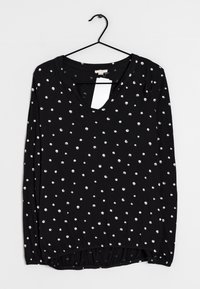 Schwarzes Langarmshirt mit V-Ausschnitt, versehen mit verstreuten weißen Punkten. Weicher Stoff mit einem gerafften Saum am unteren Ende. Einzelhandelsetikett angebracht.
