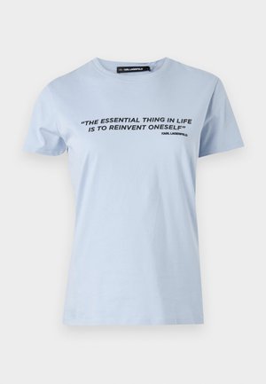 Ljusblå bomullströja med korta ärmar, med en svart texttryck: "DEN VIKTIGASTE SAKEN I LIVET ÄR ATT ÅTERUPPTÄCKA SIG SJÄLV."