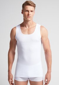 Hvid bomulds tanktop med rund halsudskæring og brede skulderstropper, med ribbet tekstur og tætsiddende pasform.