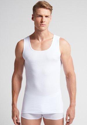 White cotton tank top with a round neckline and wide shoulder straps, featuring a ribbed texture and a fitted design.