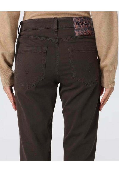 Jeans en denim marron avec des poches arrière, une étiquette en cuir et une coupe ajustée. La texture est lisse et la couleur est profonde et uniforme.