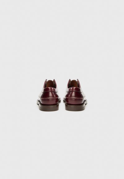 Scarpe in pelle bordeaux con finitura liscia, punta arrotondata, tacco basso e dettagli bianchi a contrasto lungo i lati e il tallone.