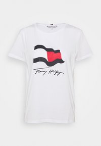 Camiseta de algodón blanca con un gráfico de una bandera ondeando en negro, rojo y blanco, con el texto "Tommy Hilfiger" impreso debajo.