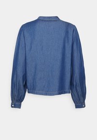 Giacca di jeans con design cropped, maniche lunghe e puffate, e polsini con bottone. Presenta un colletto classico e una finitura liscia, leggermente strutturata.