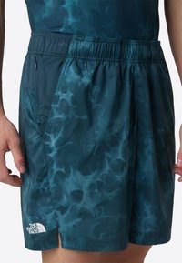 Men's athletic shorts in dark teal with a swirling pattern, made from lightweight material. Features an elastic waistband and side pocket.