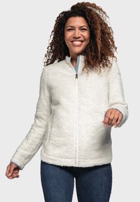 Veste en polaire blanche avec un extérieur texturé et shaggy, fermeture éclair sur le devant et poches latérales. Présente des poignets côtelés avec des accents bleus.