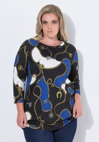 Svart topp med guld kedja och blå mönster, med trekvartsärmar. Slät textur med rund halsringning och lekfulla detaljer.