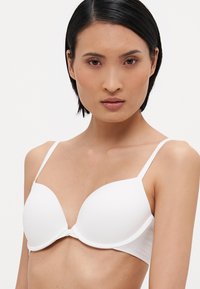 White padded bra with adjustable straps, smooth texture, and seamless design. Features a subtle underwire for support.