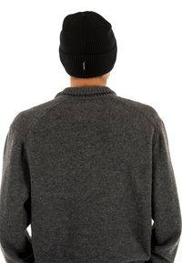 Czarna, prążkowana czapka noszona przez osobę w ciemnoszarym swetrze z okrągłym dekoltem i subtelną fakturą.