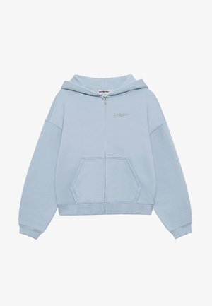 Sudadera de cremallera en azul claro, hecha de tela suave, con un bolsillo tipo canguro, mangas anchas y un logo bordado en el pecho. Textura suave.