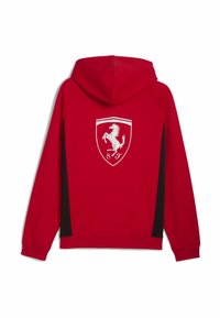 Červená mikina s kapucí a černými bočními detaily, na zadní straně s bílým logem Ferrari, vyrobená z měkké, texturované tkaniny.