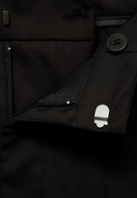 Čierne látkové nohavice s vreckom na zips, detailom s gombíkom a strieborným akcentom. Majú hladkú textúru a strih, ktorý sa pekne prispôsobuje postave.