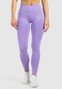 Lila leggings van rekbaar materiaal, met een hoge tailleband en een gladde textuur. Draagt met witte sport schoenen.