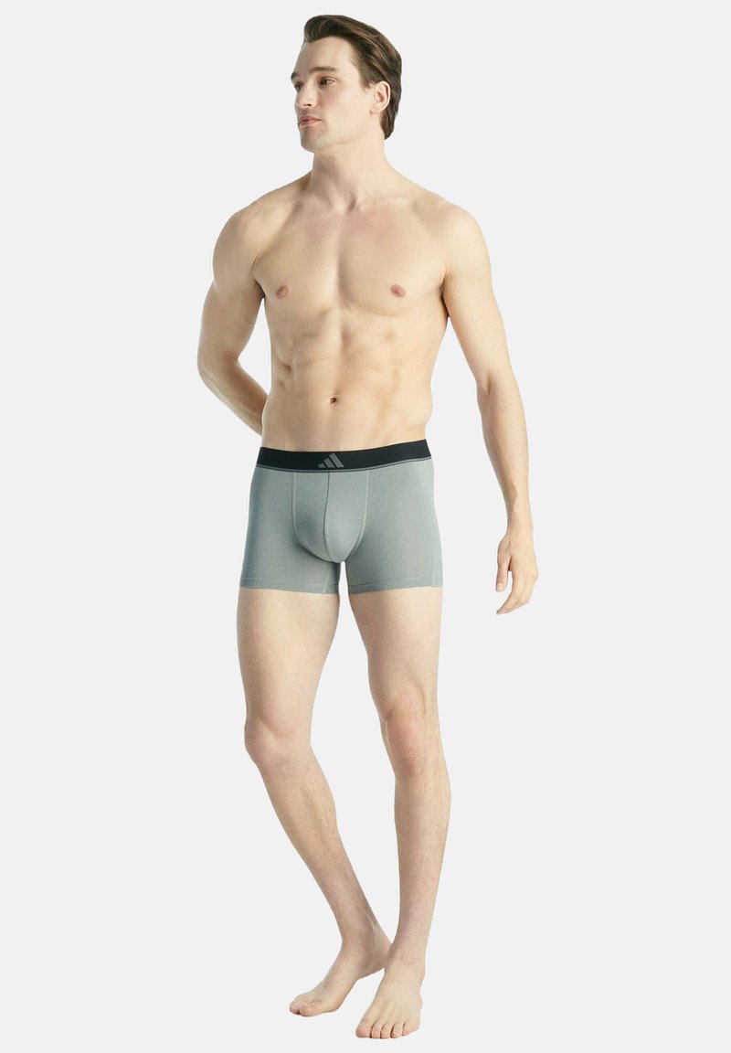 Caleçons boxers gris avec une taille élastique noire et un logo, présentant un design ajusté et un tissu lisse et extensible.