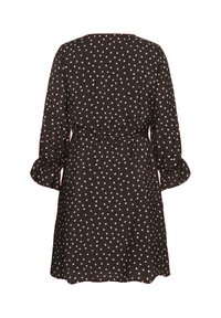 Robe noire à pois blancs, manches longues avec poignets volantés et taille cintrée, vue de dos sur fond blanc.