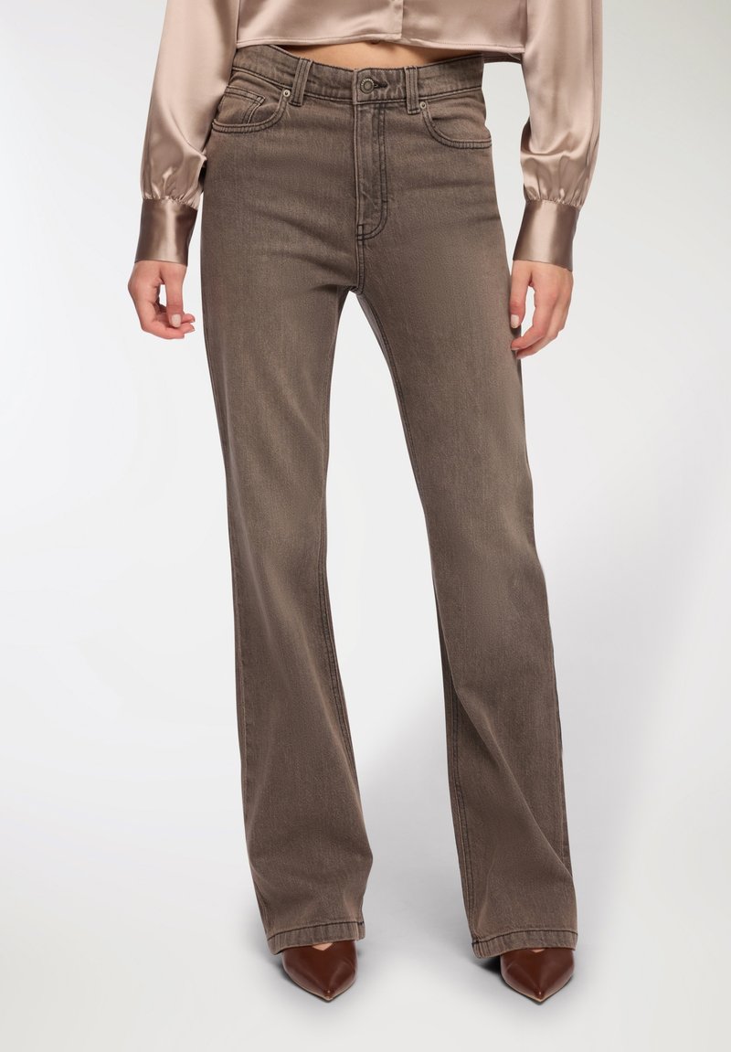 Brązowe dżinsy flare z wysokim stanem. Tkanina ma lekki połysk i subtelną fakturę, z klasycznymi kieszeniami i szlufkami na pasek.