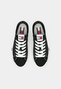 Μαύρα πάνινα αθλητικά παπούτσια με λευκά κορδόνια, γκρι εσωτερική επένδυση και πολύχρωμο ριγέ λογότυπο στη γλώσσα. Λαστιχένια σόλα.