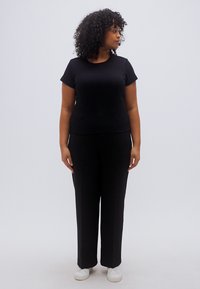 Μαύρο κοντομάνικο μπλουζάκι σε συνδυασμό με μαύρο παντελόνι φαρδιάς γραμμής. Το σύνολο έχει ομαλή υφή και εφαρμοστή σιλουέτα, κατάλληλο για casual εμφάνιση.