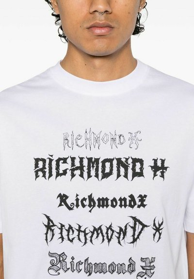 T-shirt bianco in cotone con diversi design di testo stilizzati in nero, con caratteri e dimensioni variabili, che mostrano in modo prominente la parola "Richmond".