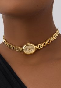Orologio choker in tono oro con design a catena collegata e quadrante ovale con lancette chiare e dettagli minimalisti.