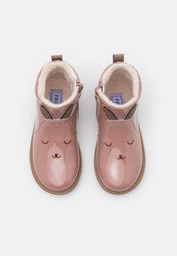 Růžové lakované kotníkové boty s chlupatým podšívkou, s designem králičí tváře a třpytivými akcenty na uších. Lehké gumové podrážky.