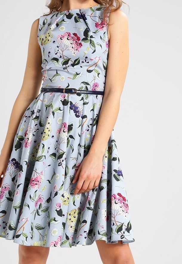 Blommig klänning i ljusblått med livliga rosa, gula och gröna mönster. Ärmlös design med figursydd överdel och utsvängd kjol.