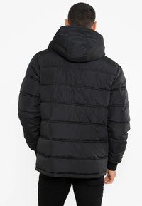 Czarna kurtka puchowa z kapturem, posiadająca pikowaną konstrukcję, ściągacze na mankietach i prosty krój, wykonana z lekkiego, wodoodpornego materiału.