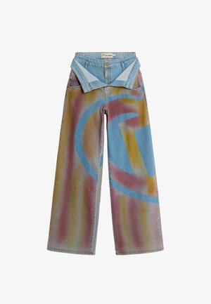 Laiade lõikega teksapüksid, millel on mitmevärviline tuhmoranžide ja lillade toonide pihustatud muster ning geomeetrilised sinised kujundid, vöökoha juurest kokkupandud.