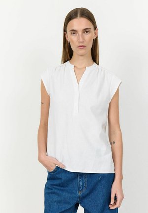 Witte top met korte mouwen en een mandarin kraag, met een knoopsluiting en subtiele plooien op de schouders, gecombineerd met blauwe jeans.