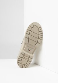 Beige Gummisohlen mit einem strukturierten Profil. Verfügt über ein prägedrucktes Logo und Größeninformationen. Texturierte Oberfläche für besseren Halt.