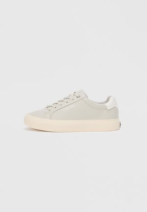 Svijetlosivi tenisice s glatkom teksturom, okruglim vrhom i bijelim vezicama. Imaju bež potplat i suptilno brendiranje sa strane.