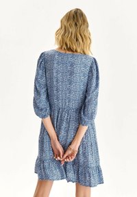Elegantes blaues Blumenkleid mit 3/4-Puffärmeln, gerafftem Taillenteil und gestuftem Rüschensaum, aus leichtem Stoff mit dezentem Muster.