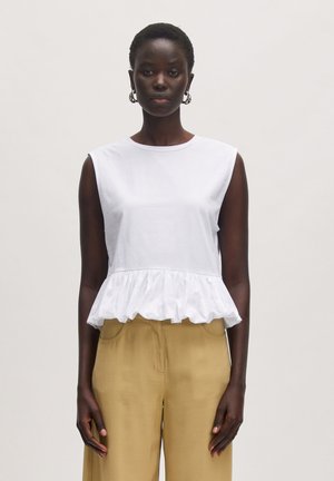 Witte mouwloze top met een gerimpelde zoom, gemaakt van lichte stof, gecombineerd met khaki wijde broek met een ontspannen pasvorm.
