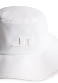 Vit bucket hat med slät textur, rundad krona och bred skärm. Har en upphöjd, minimalistisk logotyp på framsidan.