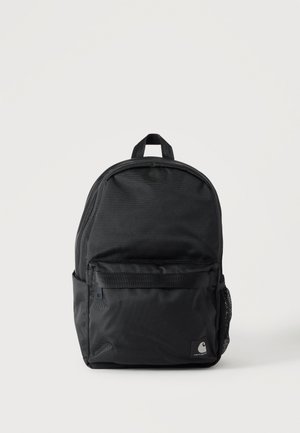 Sac à dos en tissu noir avec poche avant zippée, poche latérale en filet et poignée de transport supérieure sur un fond clair uni.