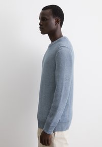 Blauer Strickpullover mit strukturiertem Muster, Rundhalsausschnitt und gerippten Bündchen. Langärmliges Design mit lockerer Passform.
