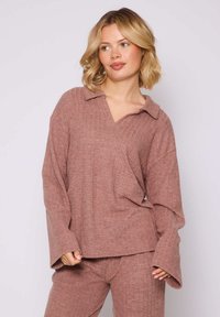 Pullover a maglia a coste in rosa polveroso con colletto e scollo a V, caratterizzato da maniche lunghe e ampie e una vestibilità rilassata. Visibili pantaloni abbinati.