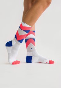 Colorful socks featuring a geometric pattern with pink, blue, and white sections. The toe and top bands are bright pink, made of textured fabric.