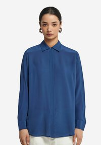 Blauses Langarmhemd aus glattem Material mit kragenförmigem Ausschnitt, Knopfleiste und geradem Saum. Verfügt über eine lockere Passform und geknöpfte Ärmel.