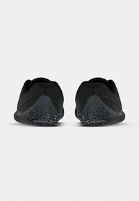 Par svart Merrell slip-on-skor visade bakifrån, med texturerade gummisulor och en minimalistisk design mot en enfärgad bakgrund.