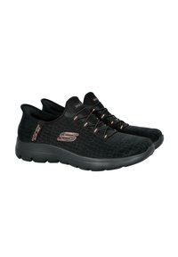 Zapatillas deportivas negras con parte superior de tejido texturizado, cordones elásticos y suela acolchada. Presenta un sutil logo en metálico rosa dorado.