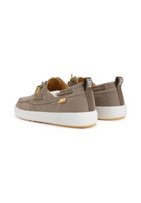 Brown canvas sneakers with contrasting white rubber soles, rounded shape, yellow accents, and visible branding on the heel.