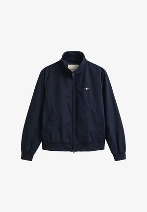 Chaqueta ligera azul marino con cremallera frontal, cuello mao, dos bolsillos laterales, mangas con puños y pequeño logo en el pecho.