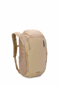 Sac à dos Thule en beige, avec un design épuré, des bretelles rembourrées, des compartiments zippés et un tissu texturé pour la durabilité.