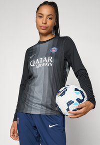 Black and gray long-sleeve sports shirt with vertical stripes, featuring "QATAR AIRWAYS" logo. Navy athletic pants and a white soccer ball with blue accents.