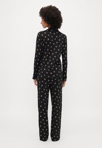 Set de pijama negru, format dintr-o bluză cu mânecă lungă și pantaloni, împodobit cu mici modele florale. Material moale, cu o croială lejeră.