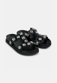 Sandali neri slip-on realizzati in pelle, con molteplici strass trasparenti sulle cinghie e una suola in gomma spessa per supporto.