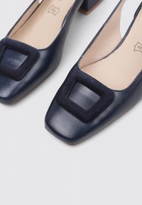 Chaussures en cuir bleu marine à talon carré avec un bout carré et des accents en velours texturé. Fini lisse avec une semelle mate.