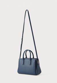 Τσάντα ώμου ναυτικού μπλε με υφή, διπλές κορυφαίες λαβές, ρυθμιζόμενο λουρί ώμου και κλείσιμο με φερμουάρ. Ορθογώνιο σχήμα με ελάχιστες λεπτομέρειες.